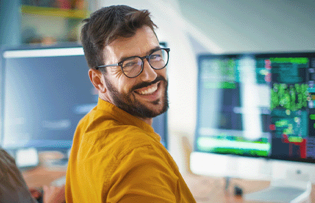 man smiling with computer screens in background